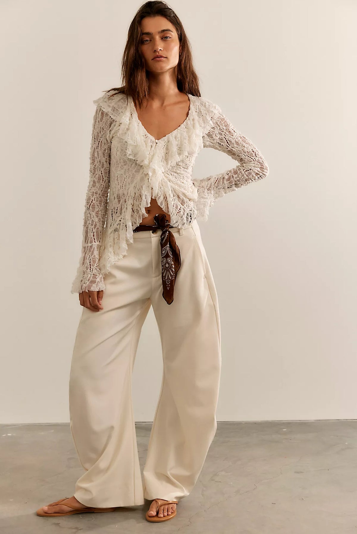 Textured lace cardigan in ivory, featuring a fitted longline silhouette, V-neckline, button-front closure, fitted long sleeves, and cascading ruffle hem detailing.