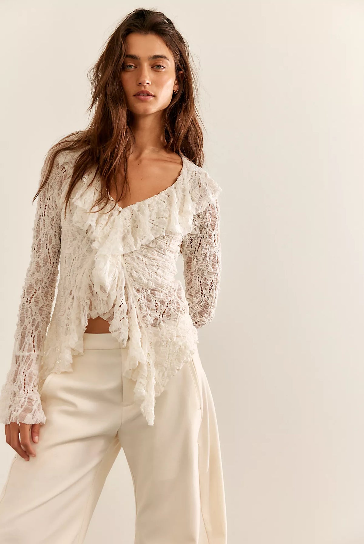 Textured lace cardigan in ivory, featuring a fitted longline silhouette, V-neckline, button-front closure, fitted long sleeves, and cascading ruffle hem detailing.