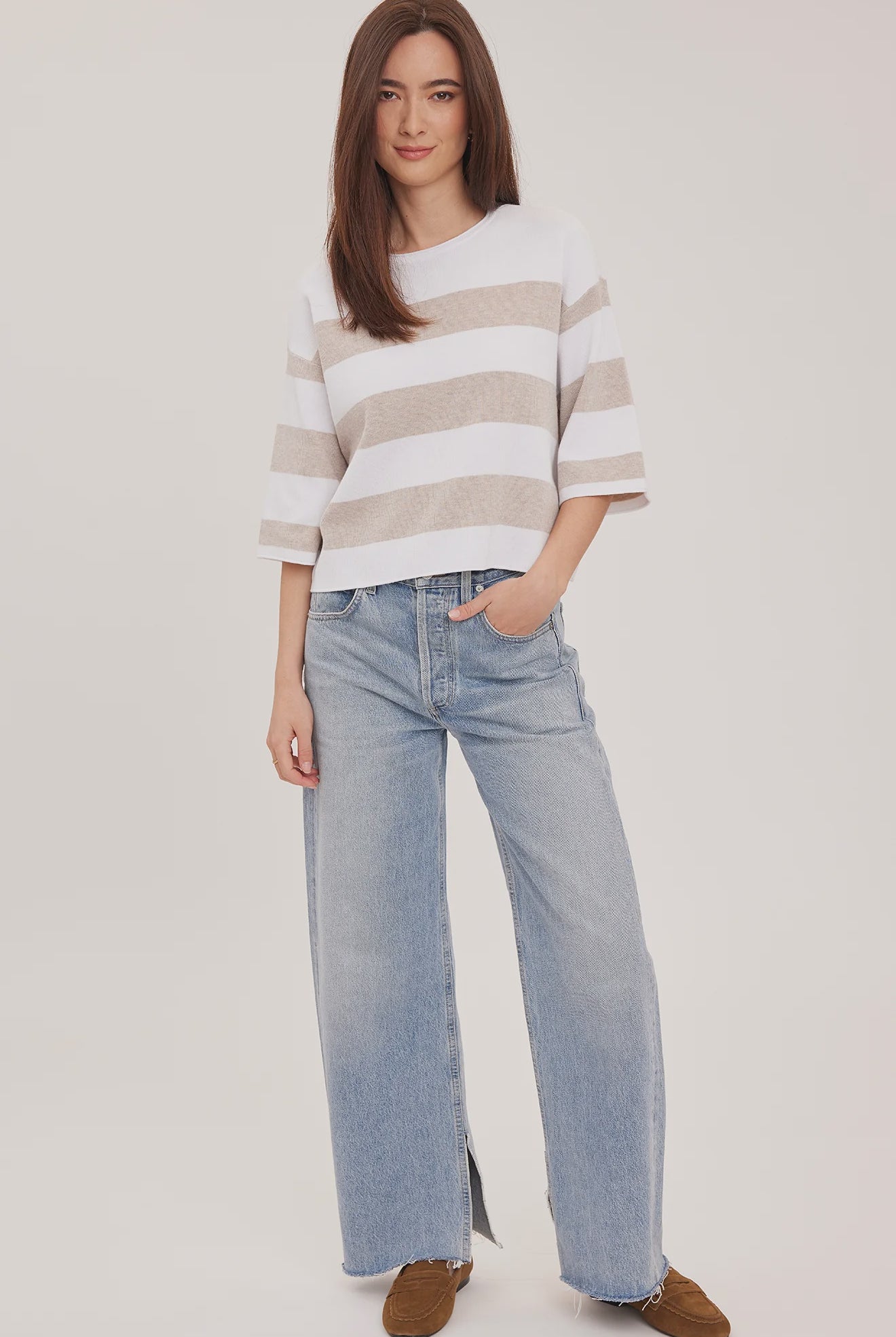 Woman wearing the Gentle Fawn Amina Knit Top in Heather Cream Stripe, featuring a relaxed fit, crew neckline, rolled hem details, and soft beige and cream horizontal stripes.