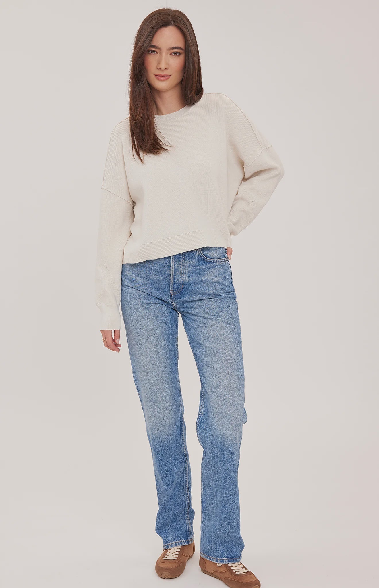 Women's cream oversized knit pullover sweater featuring a classic crew neckline, exposed seam detailing, side slits, and a soft textured half-cardigan stitch.