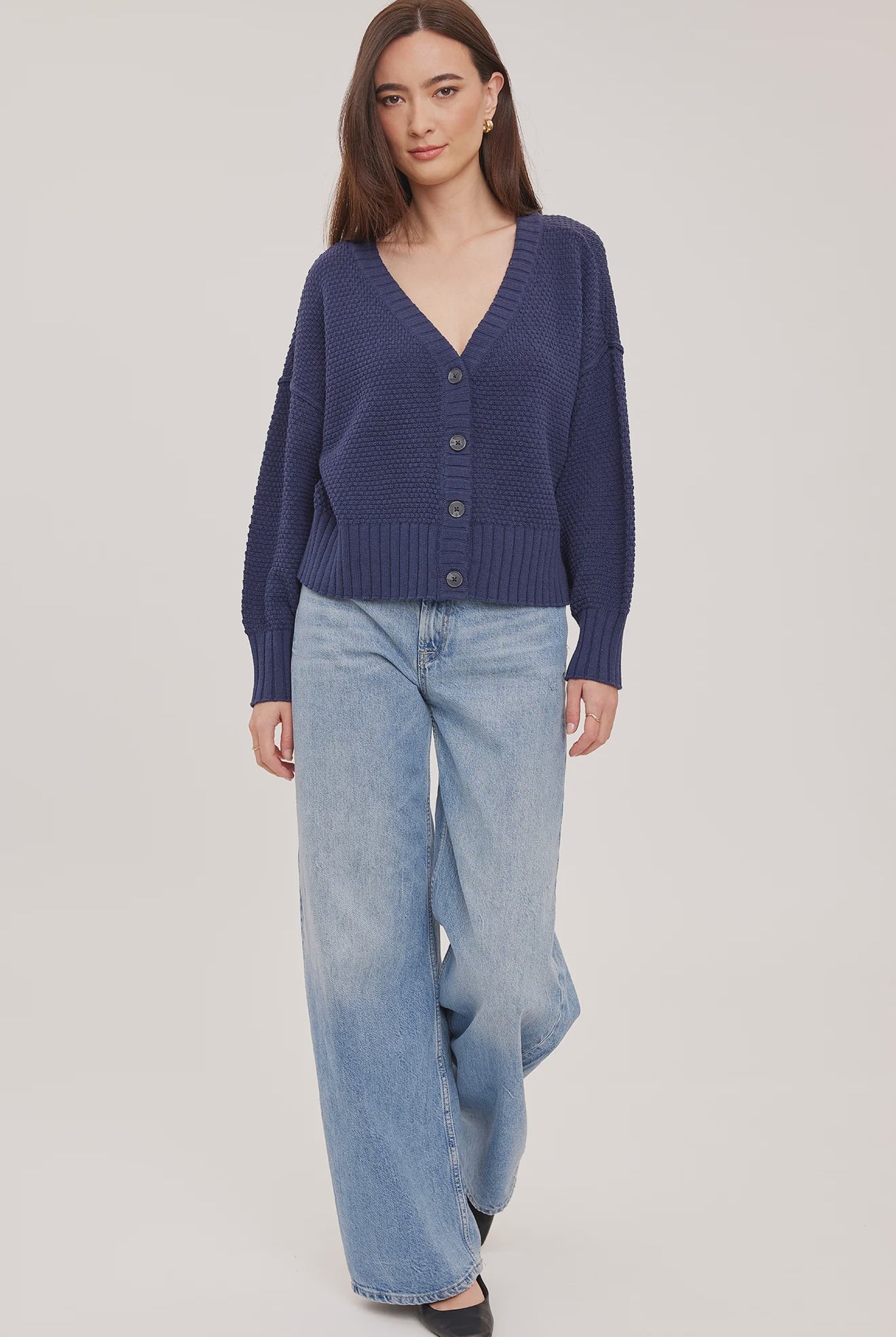 Woman wearing the Gentle Fawn Jennalee Cardigan in Navy, featuring an oversized fit, textured cotton blend knit, front button closure, and exposed seam detailing.
