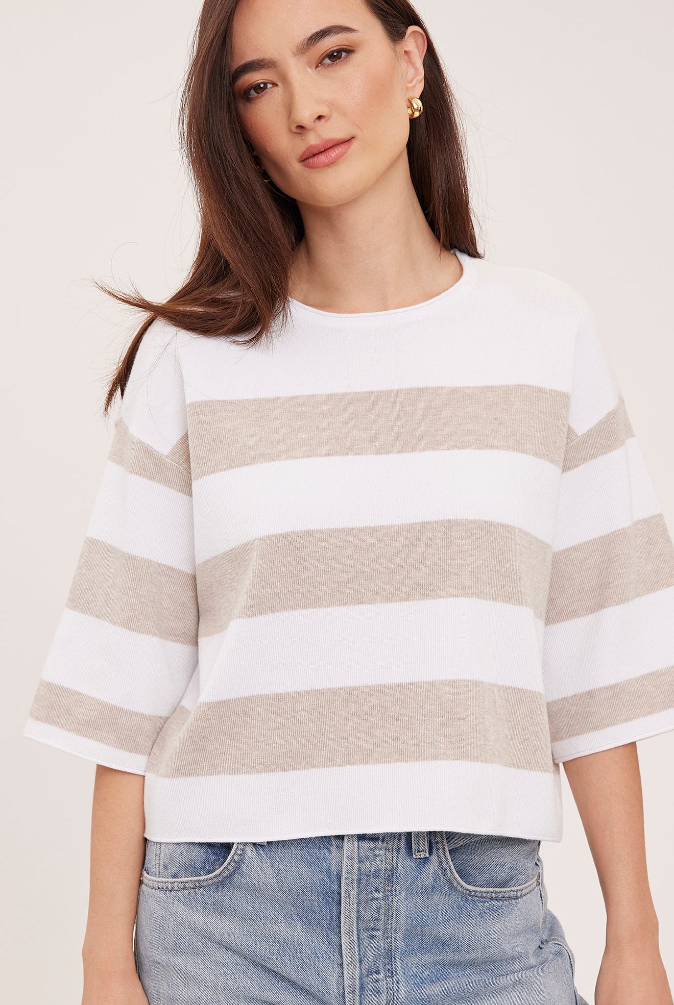 Woman wearing the Gentle Fawn Amina Knit Top in Heather Cream Stripe, featuring a relaxed fit, crew neckline, rolled hem details, and soft beige and cream horizontal stripes.