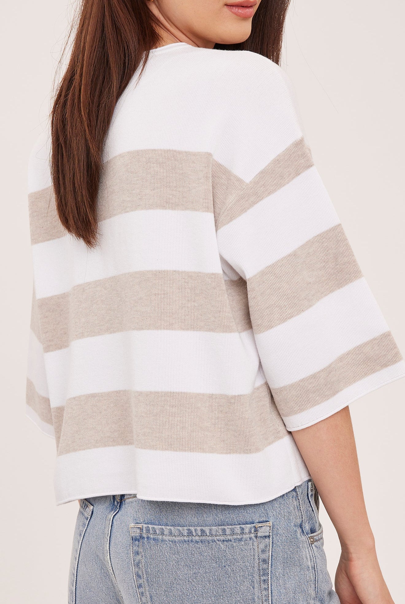 Woman wearing the Gentle Fawn Amina Knit Top in Heather Cream Stripe, featuring a relaxed fit, crew neckline, rolled hem details, and soft beige and cream horizontal stripes.