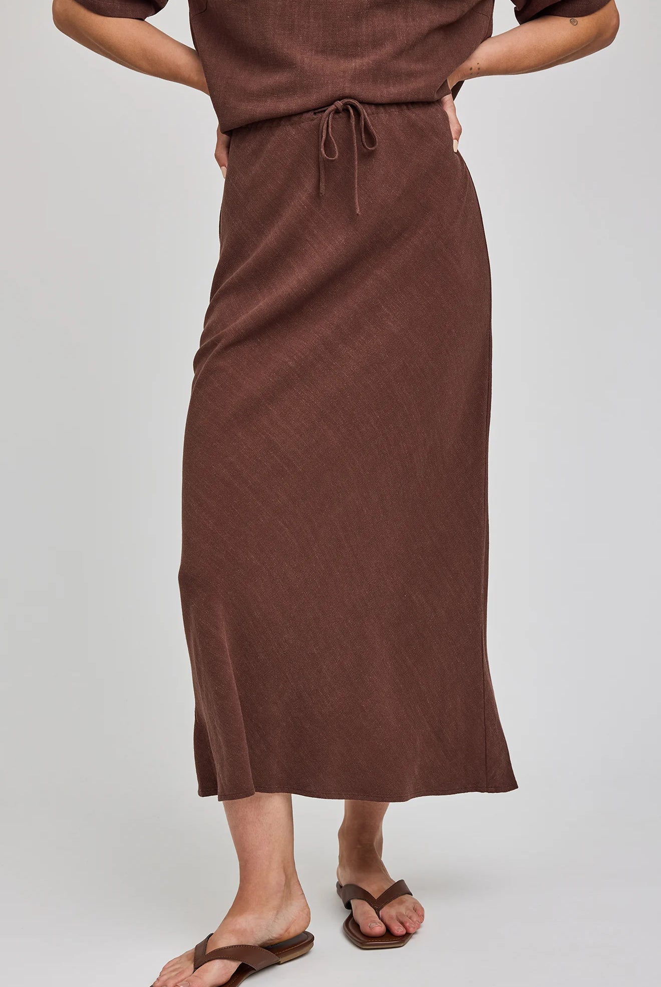 Bias-cut midi skirt in a lightweight rayon-linen blend featuring an adjustable drawstring waist for a customizable mid-rise or high-rise fit and a soft, flowing silhouette. Colour: Espresso