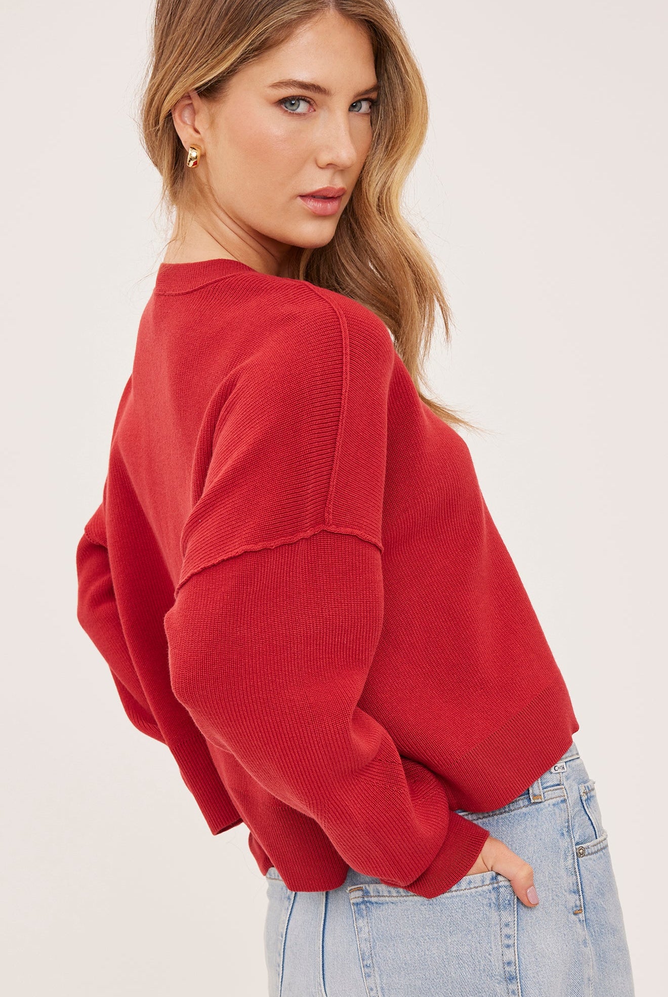 red oversized knit pullover sweater featuring a classic crew neckline, exposed seam detailing, side slits, and a soft textured half-cardigan stitch.