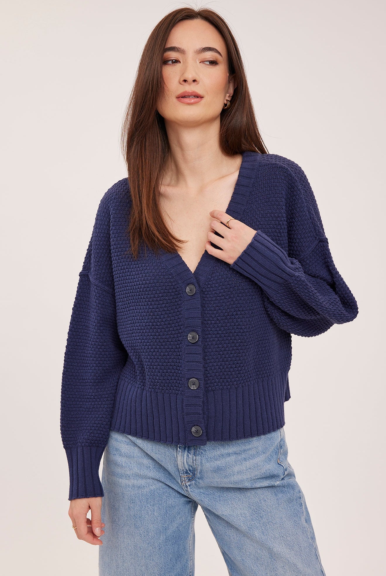 Woman wearing the Gentle Fawn Jennalee Cardigan in Navy, featuring an oversized fit, textured cotton blend knit, front button closure, and exposed seam detailing.
