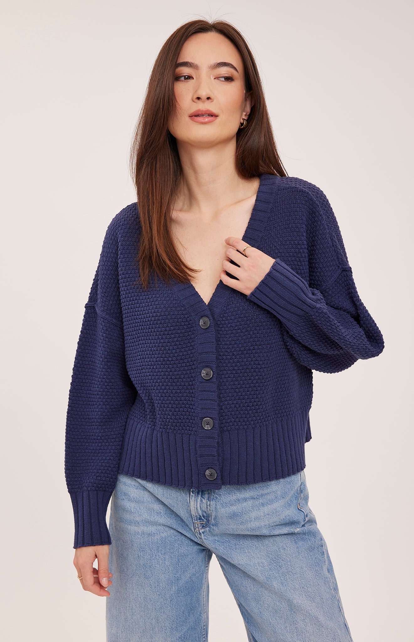Woman wearing the Gentle Fawn Jennalee Cardigan in Navy, featuring an oversized fit, textured cotton blend knit, front button closure, and exposed seam detailing.