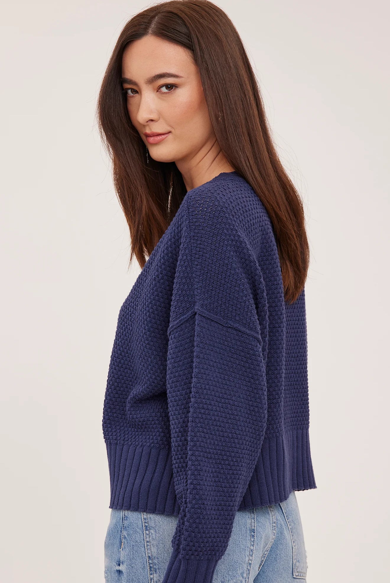 Woman wearing the Gentle Fawn Jennalee Cardigan in Navy, featuring an oversized fit, textured cotton blend knit, front button closure, and exposed seam detailing.