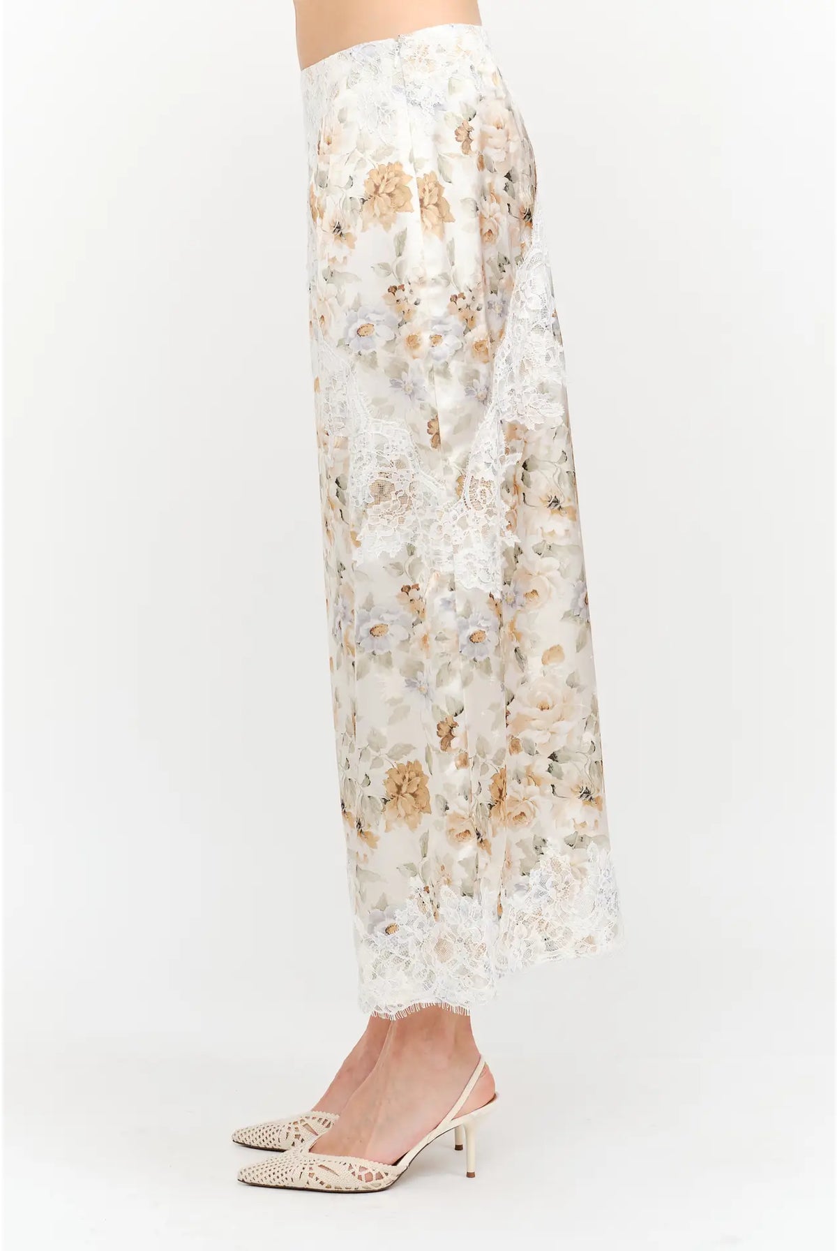 Harper Floral Midi Skirt in soft yellow and cream featuring a delicate floral print, smooth satin finish, white lace panel detailing, and a flowing midi-length silhouette.