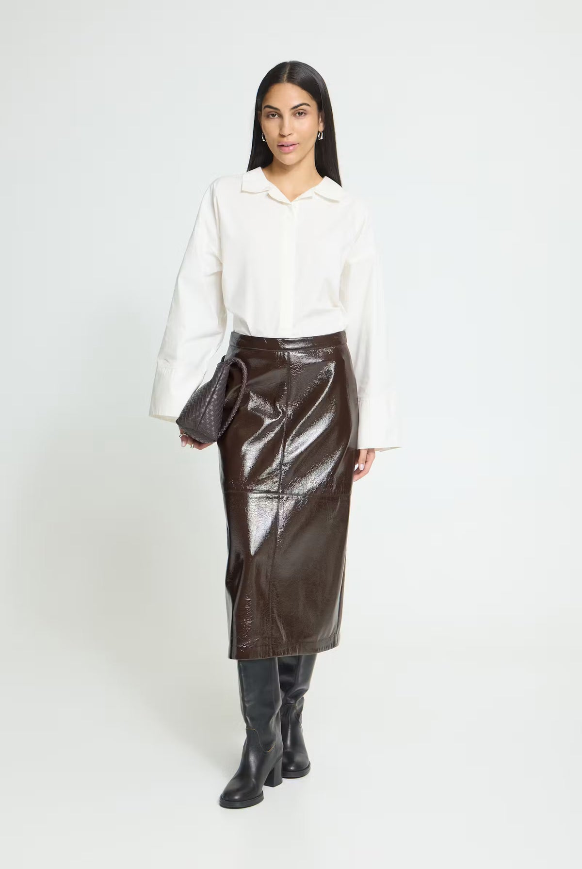 Brown High-waisted midi skirt featuring a straight silhouette, glossy textured finish, subtle panel stitching, and an exposed back zipper for a sleek, modern look.