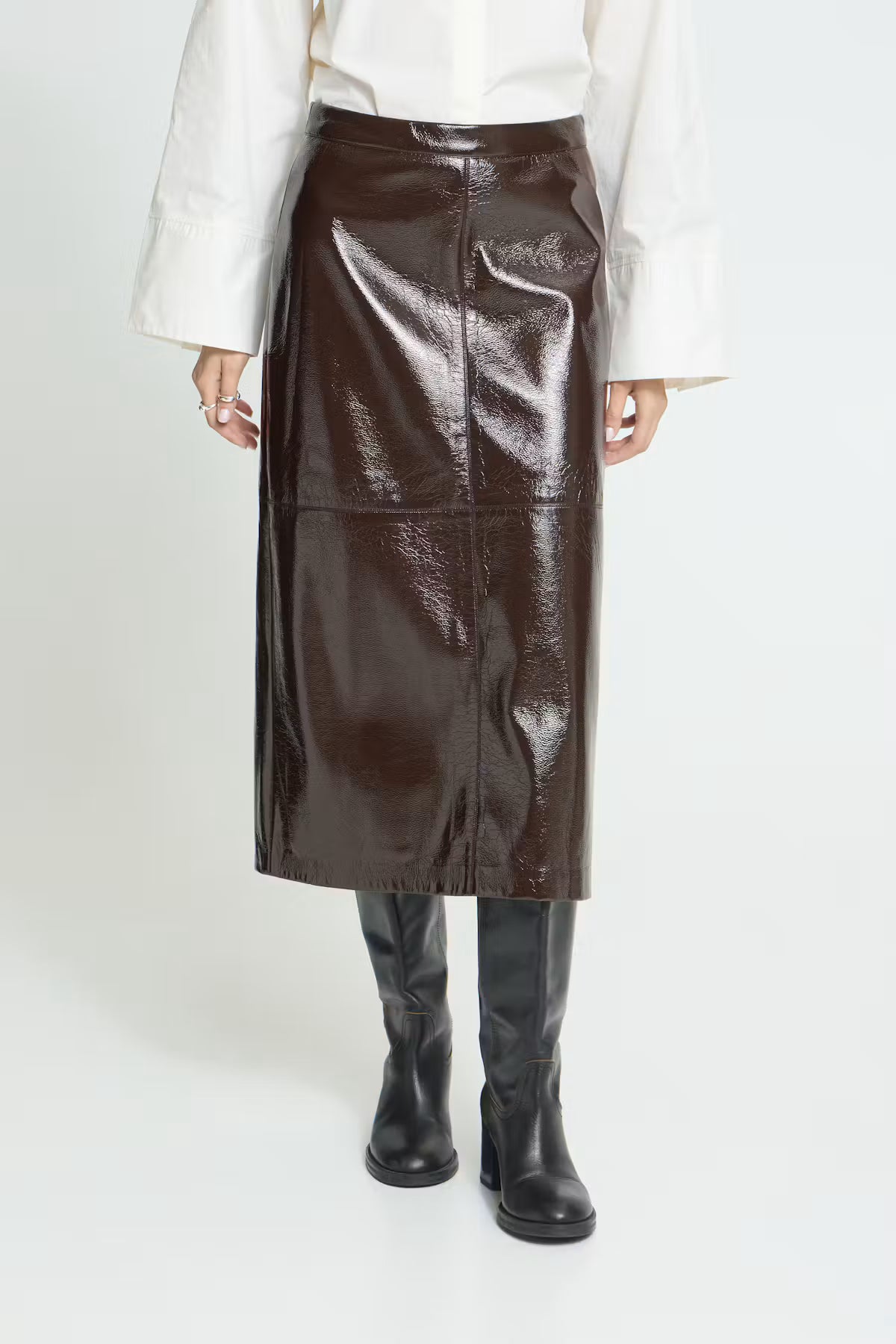 Brown High-waisted midi skirt featuring a straight silhouette, glossy textured finish, subtle panel stitching, and an exposed back zipper for a sleek, modern look.