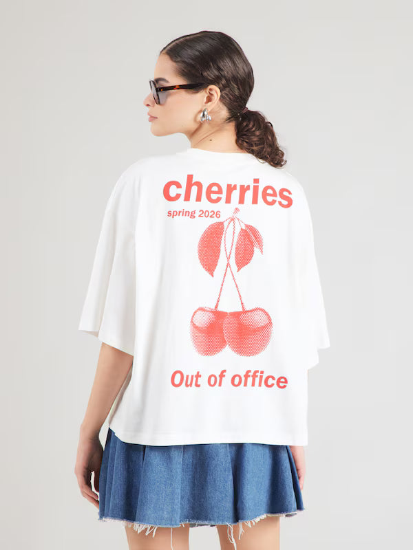 Person wearing a white t-shirt with red cherry design and text on a plain background