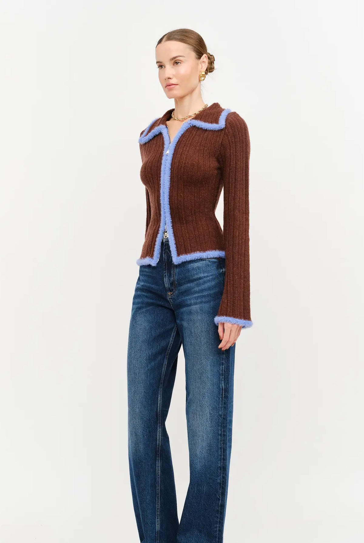 Model wearing the Jacquie Knit Top in brown, featuring a fitted silhouette, long sleeves, collared neckline, contrasting blue fuzzy trim, and two-way front zipper closure.