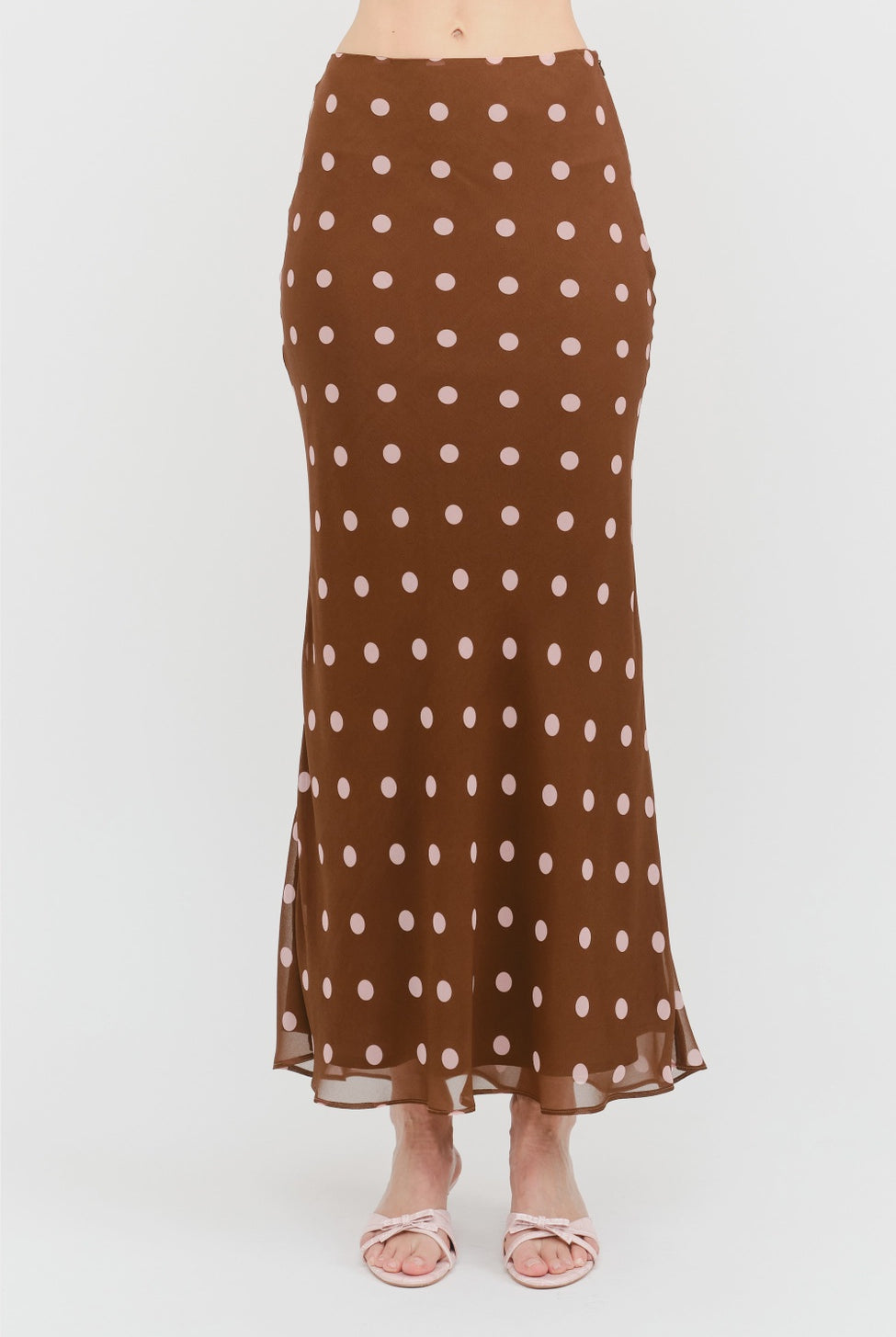 Kalila Midi Skirt in rich brown featuring soft pink polka dots, a flattering mermaid silhouette, and a flowing ankle-grazing hem.