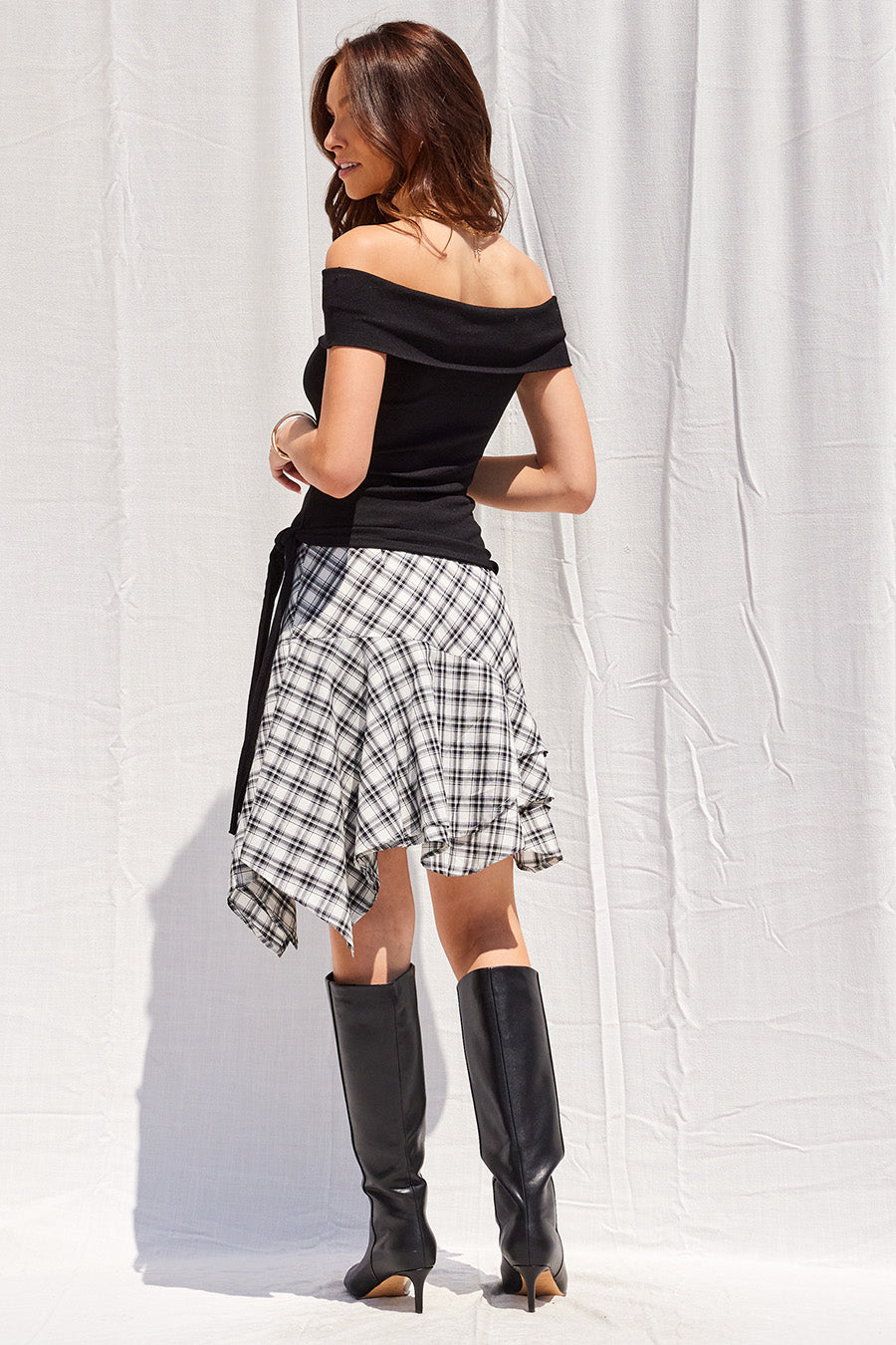 Leona checkered mini skirt featuring an asymmetrical hemline and side zipper closure, designed with a polished, feminine silhouette.