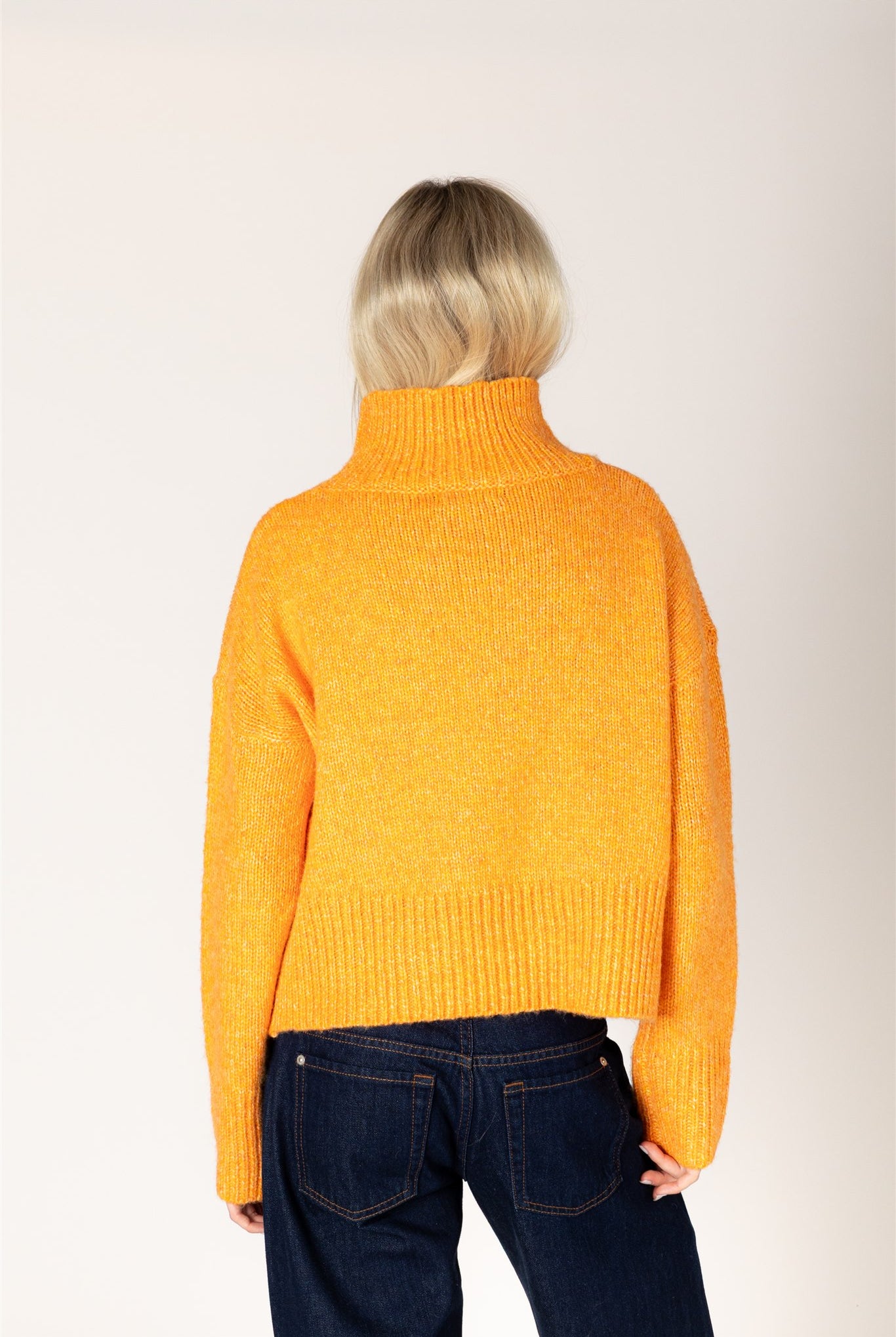 Amber yellow knit sweater featuring a mock neckline, relaxed fit, dropped shoulders, long sleeves, and ribbed cuffs and hem.
