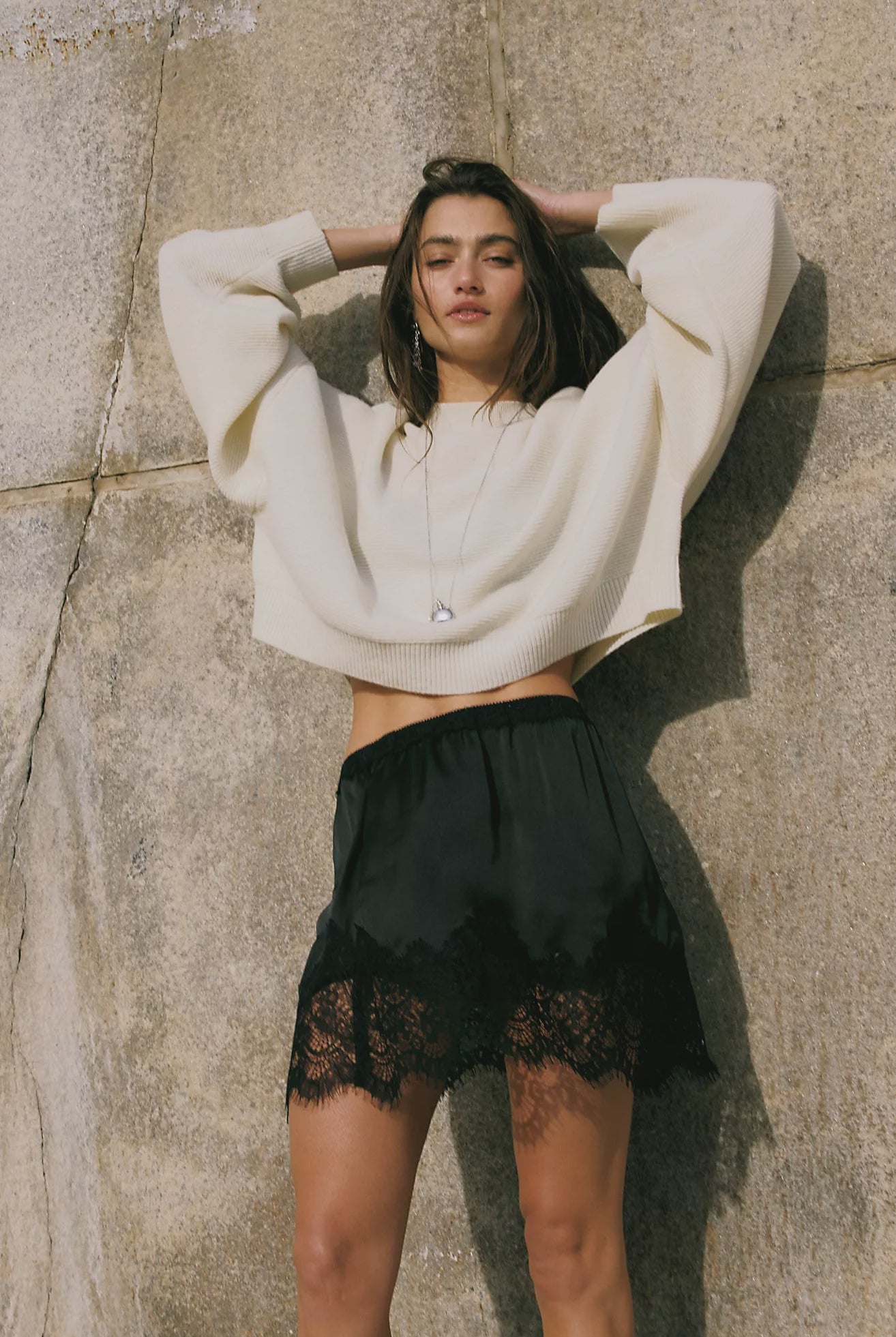 Free People Meet Me in the Middle Mini Slip Skirt in Black featuring a sleek satin finish, high-rise elastic waistband, bias-cut silhouette, and a flattering mini length.