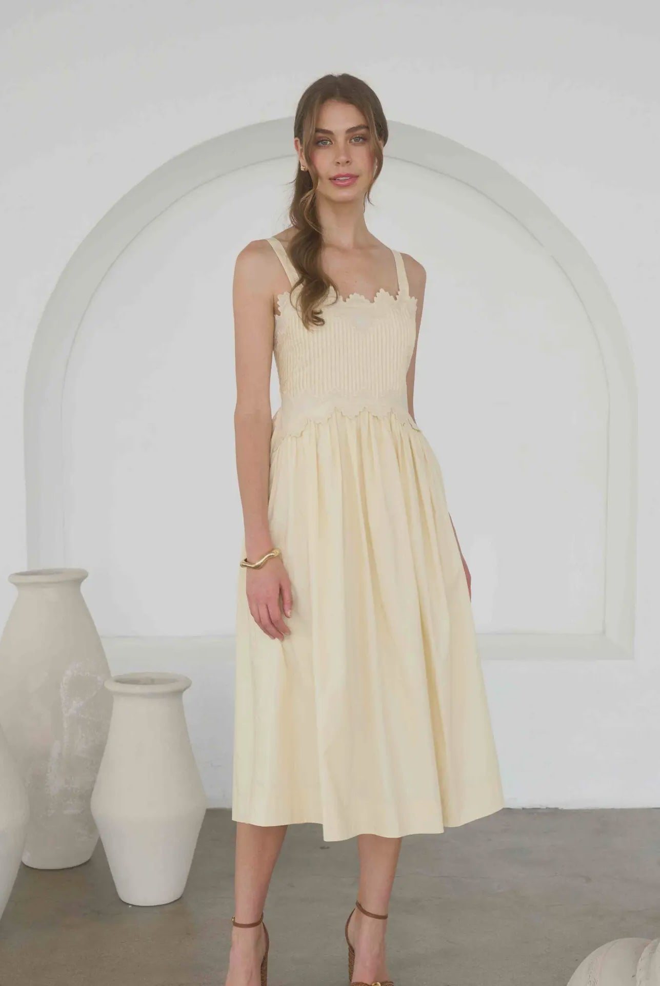 woman wearing an embroidered pintuck detail spaghetti strap midi dress in butter yellow