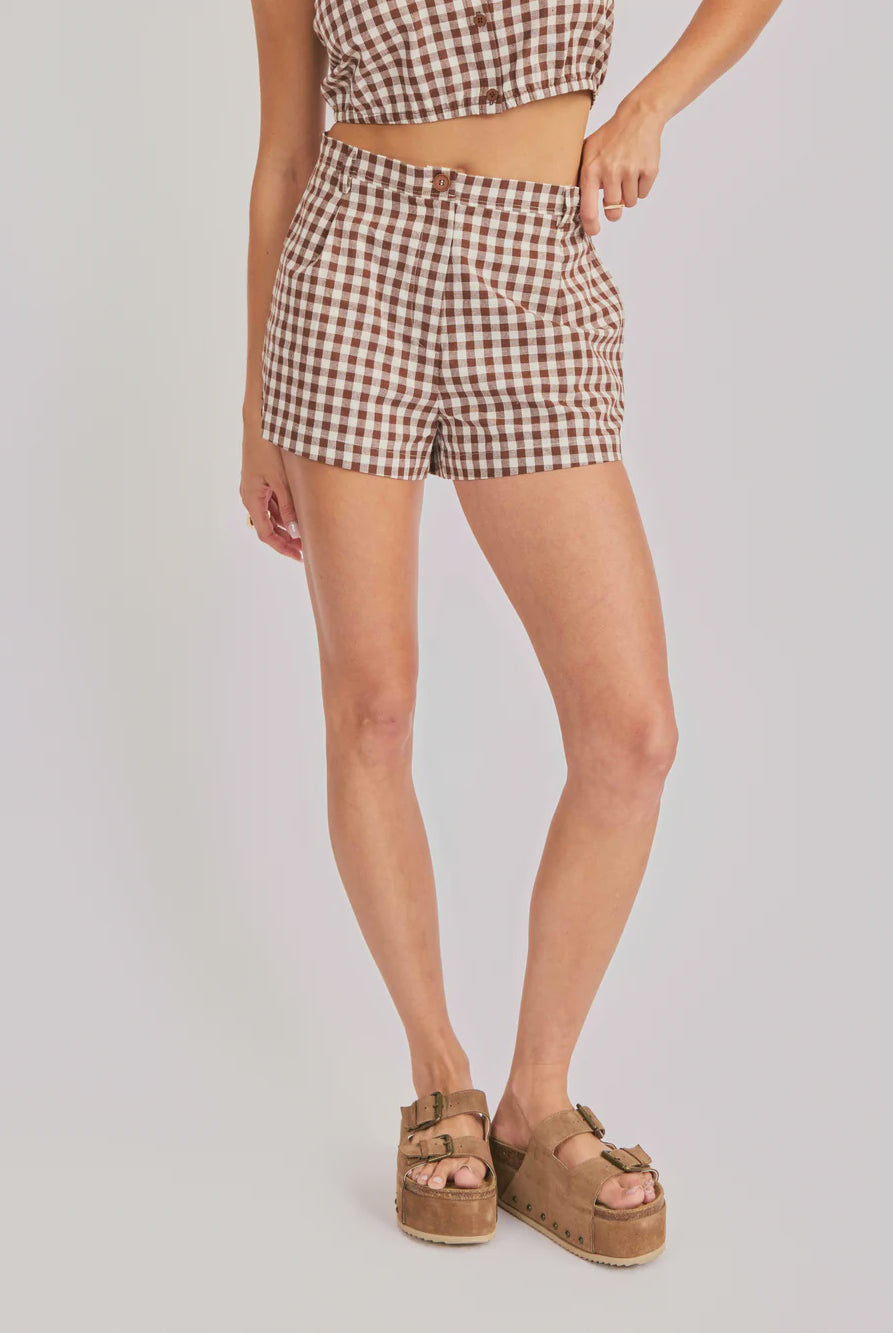 Person wearing brown and white checkered shorts on a plain background