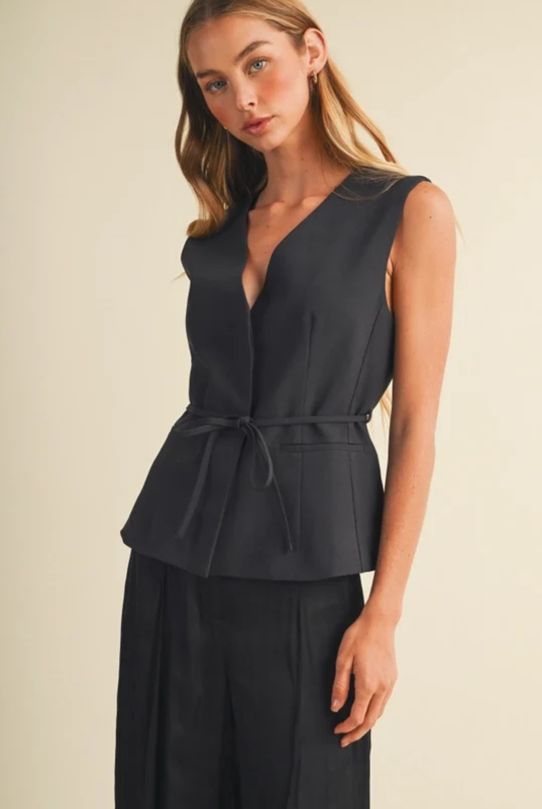 Tailored peplum top in high-density woven suiting, featuring princess seams, a deep surplice V-neckline, removable self-tie waist belt, extended shoulders, and a single-button closure.