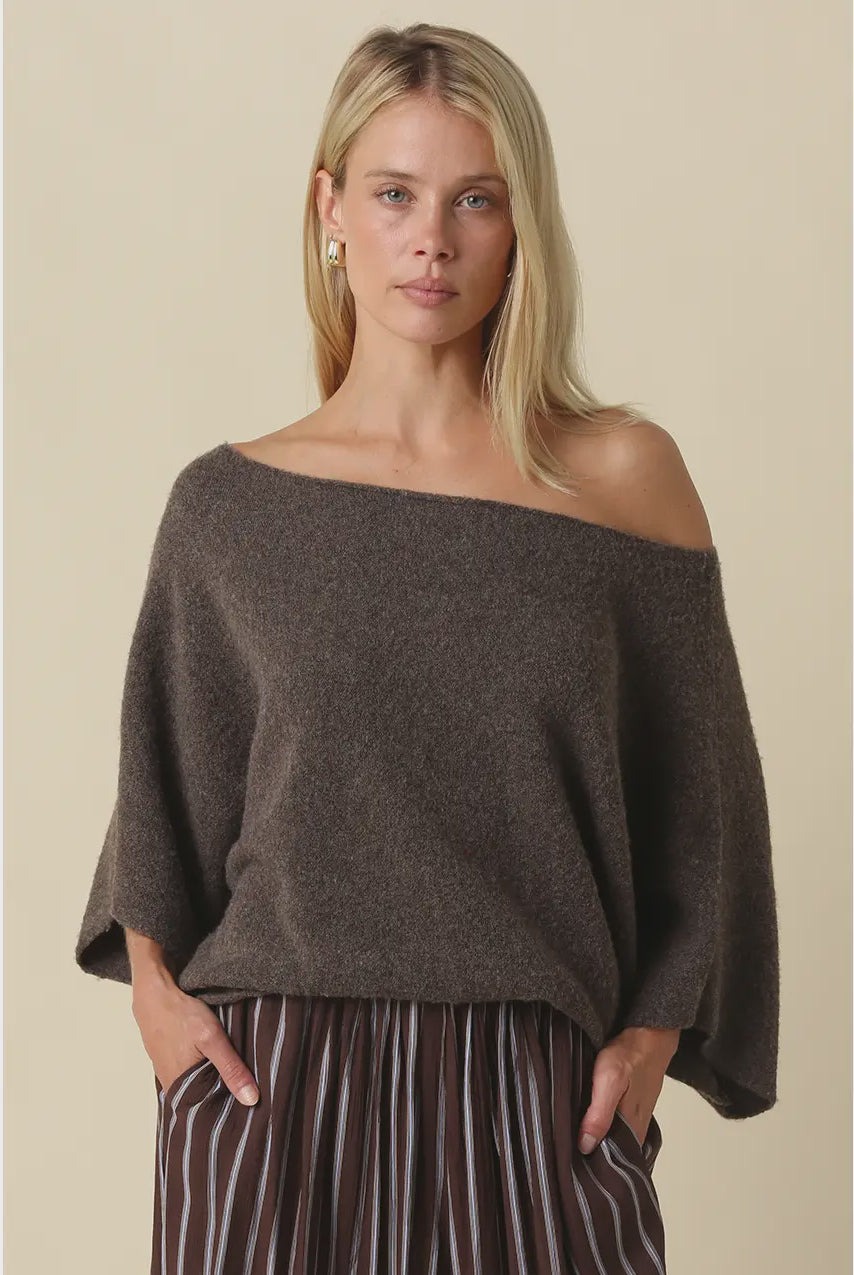 Oversized knit top with a one-shoulder neckline, dolman sleeves, textured finish, and relaxed draped fit.