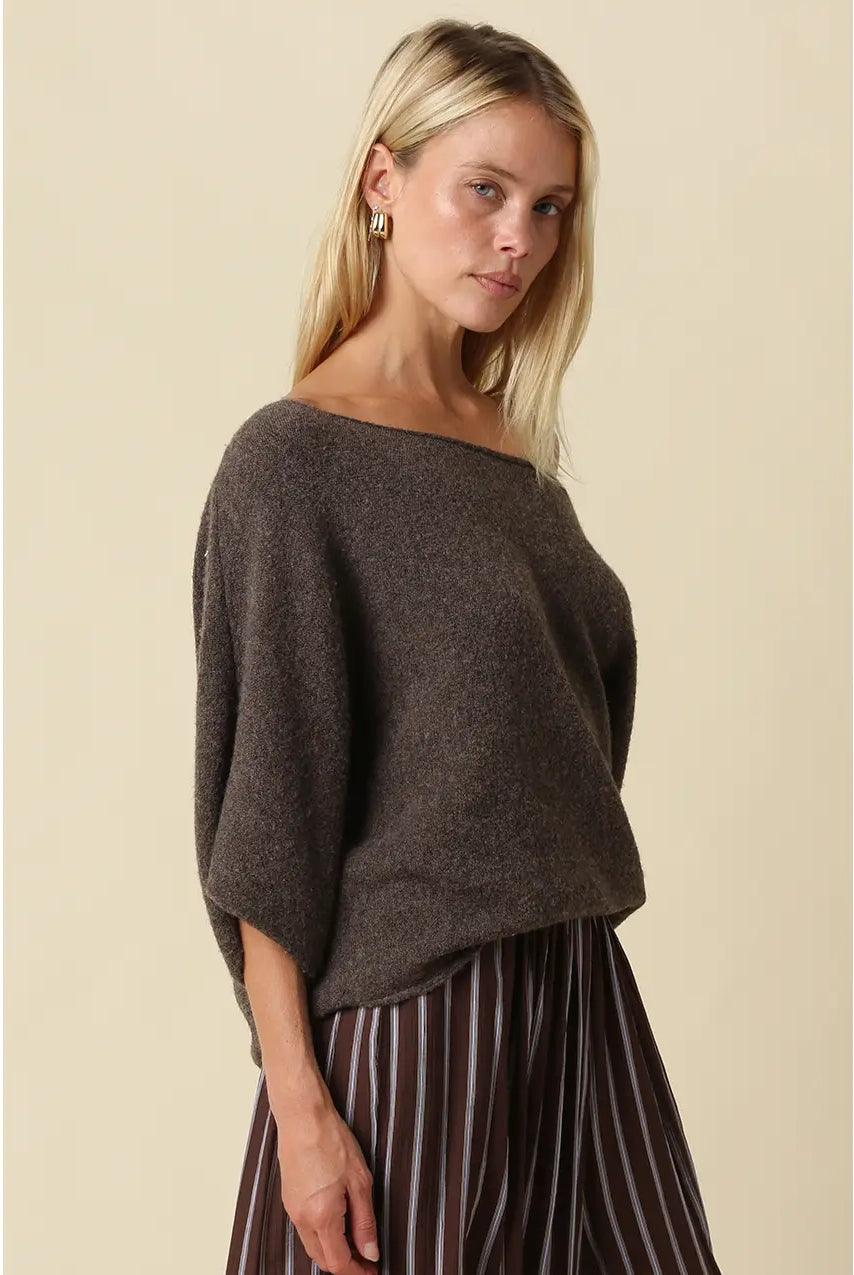 Oversized knit top with a one-shoulder neckline, dolman sleeves, textured finish, and relaxed draped fit.