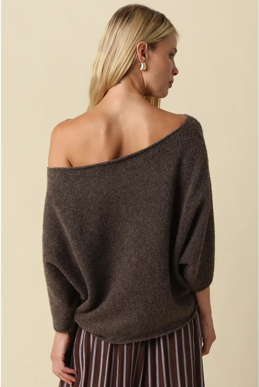 Oversized knit top with a one-shoulder neckline, dolman sleeves, textured finish, and relaxed draped fit.