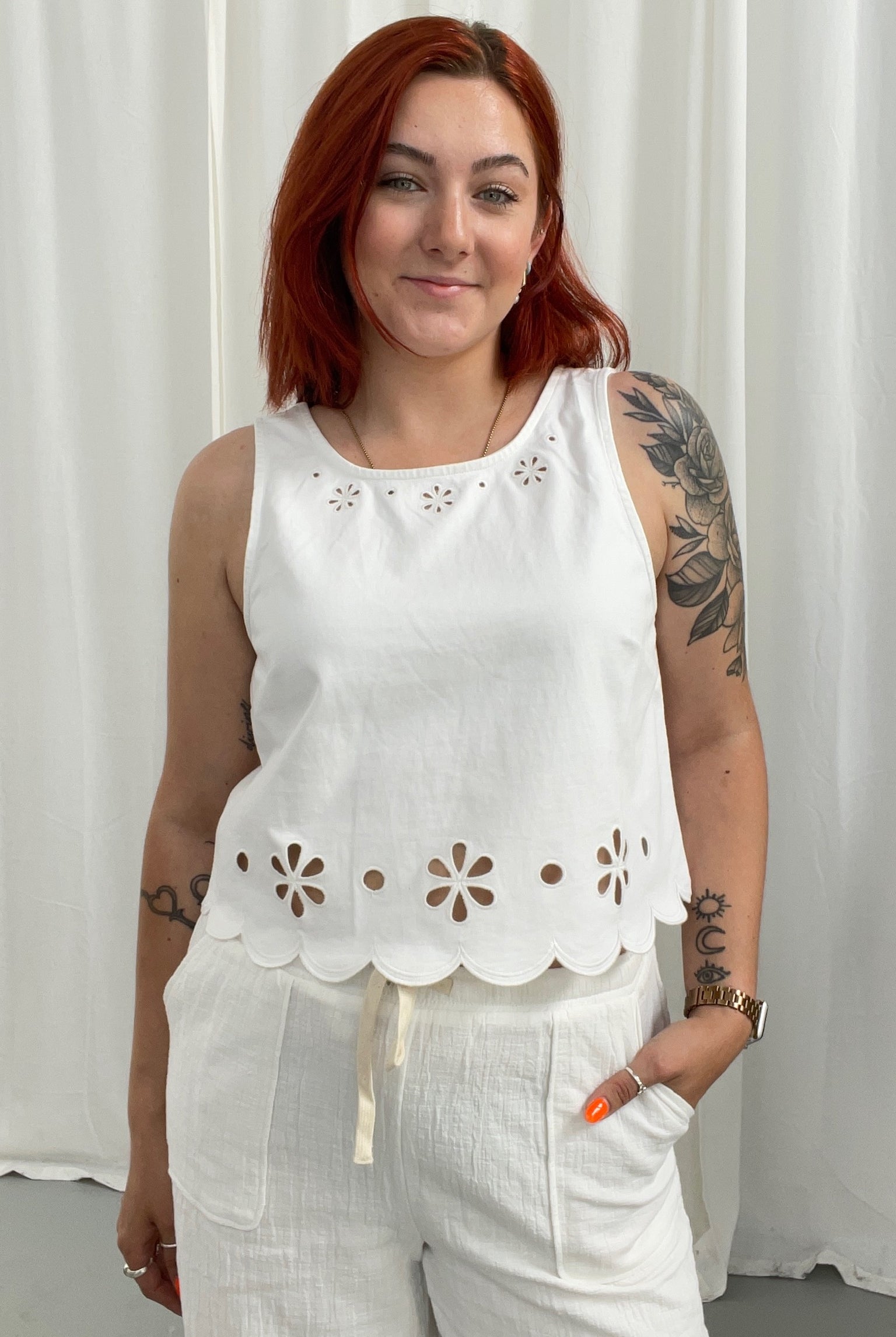 Woman wearing a white sleeveless top with floral cutouts