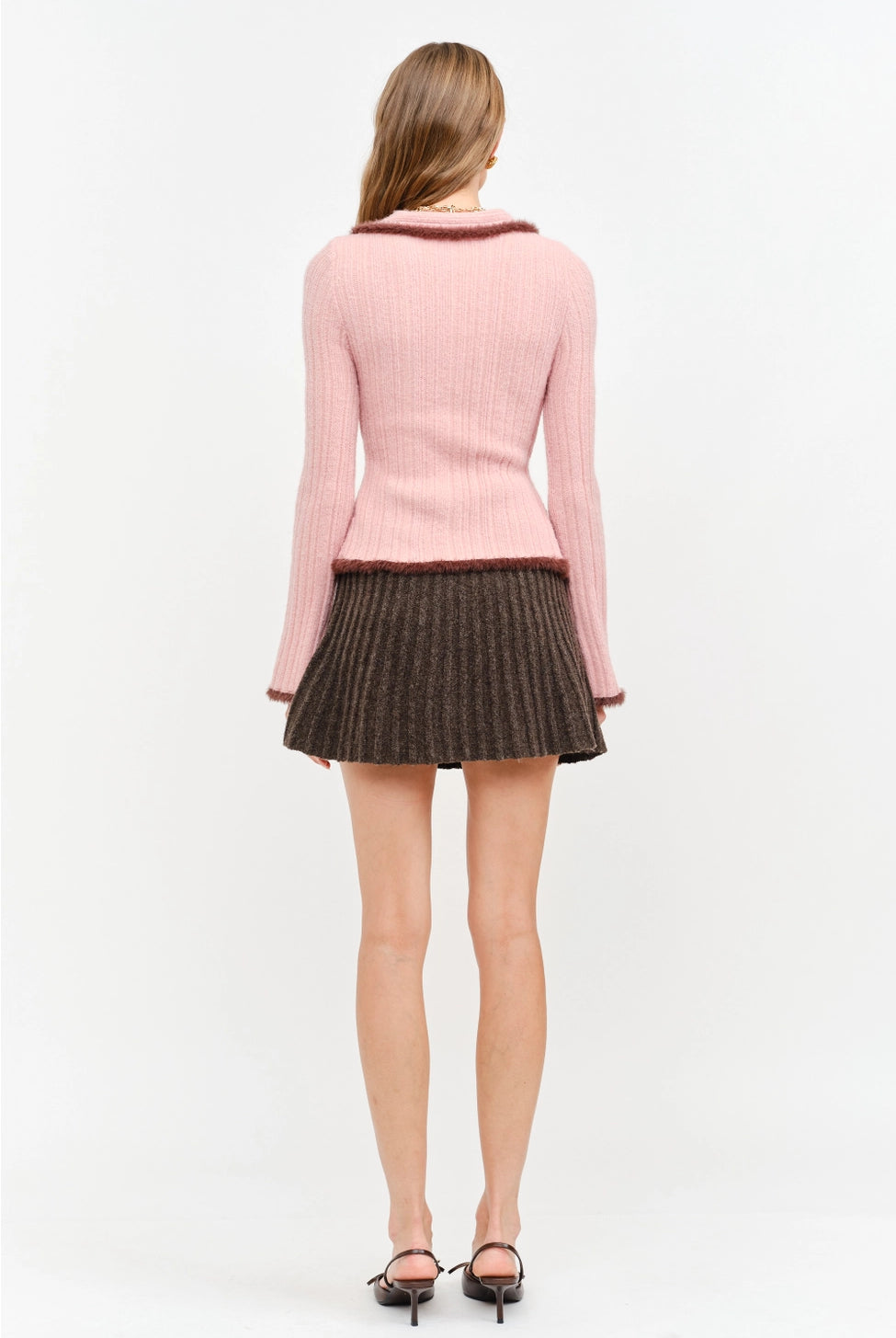 Model wearing the Jacquie Knit Top in light pink, featuring a fitted silhouette, long sleeves, collared neckline, contrasting burgundy fuzzy trim, and two-way front zipper closure.