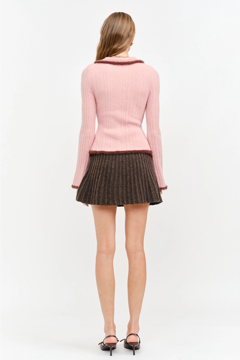 Model wearing the Jacquie Knit Top in light pink, featuring a fitted silhouette, long sleeves, collared neckline, contrasting burgundy fuzzy trim, and two-way front zipper closure.
