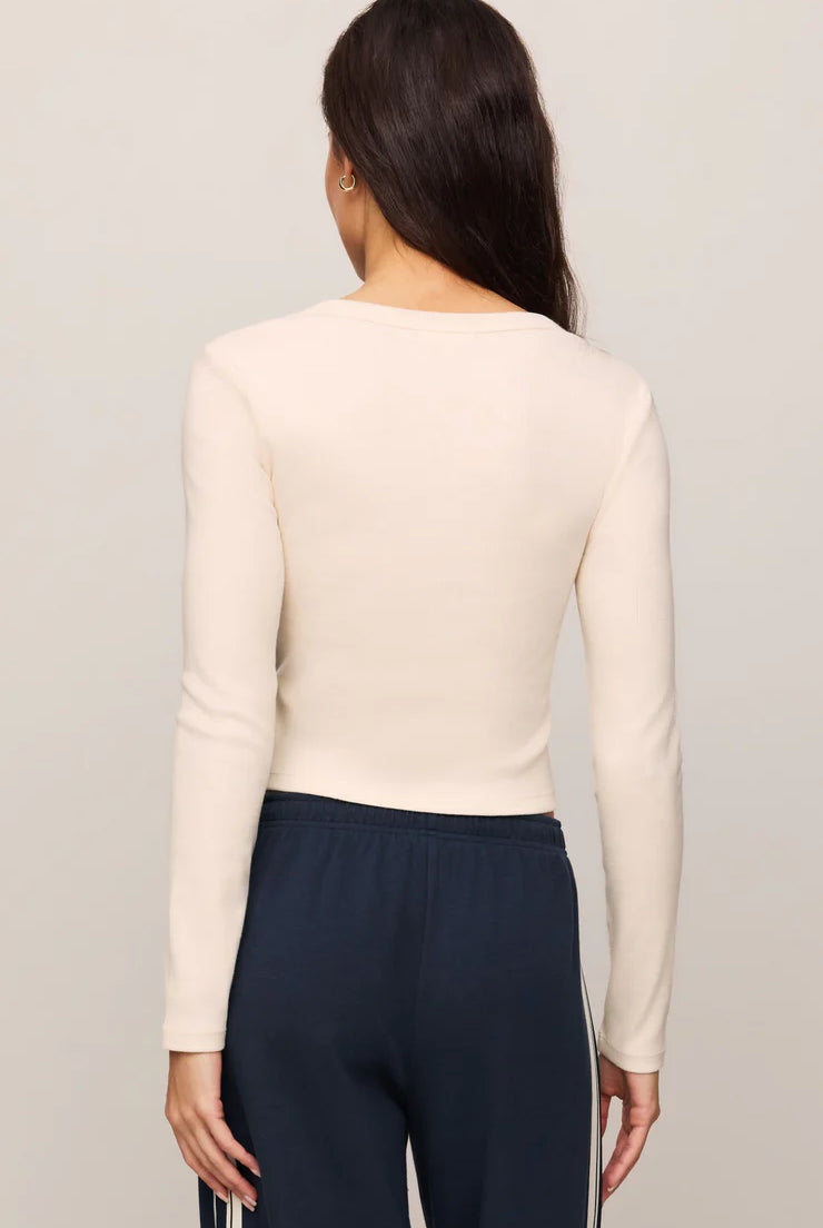 Fitted long-sleeve henley top in soft cotton modal rib fabric with a cropped silhouette, henley neckline, and functional button-front placket. The comfortable stretch fabric creates a flattering fit, making it ideal for casual wear, layering, or pairing with workout-inspired outfits.