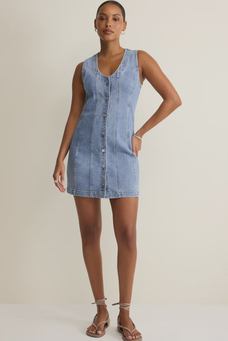 Woman wearing a denim button down mini dress against a plain background