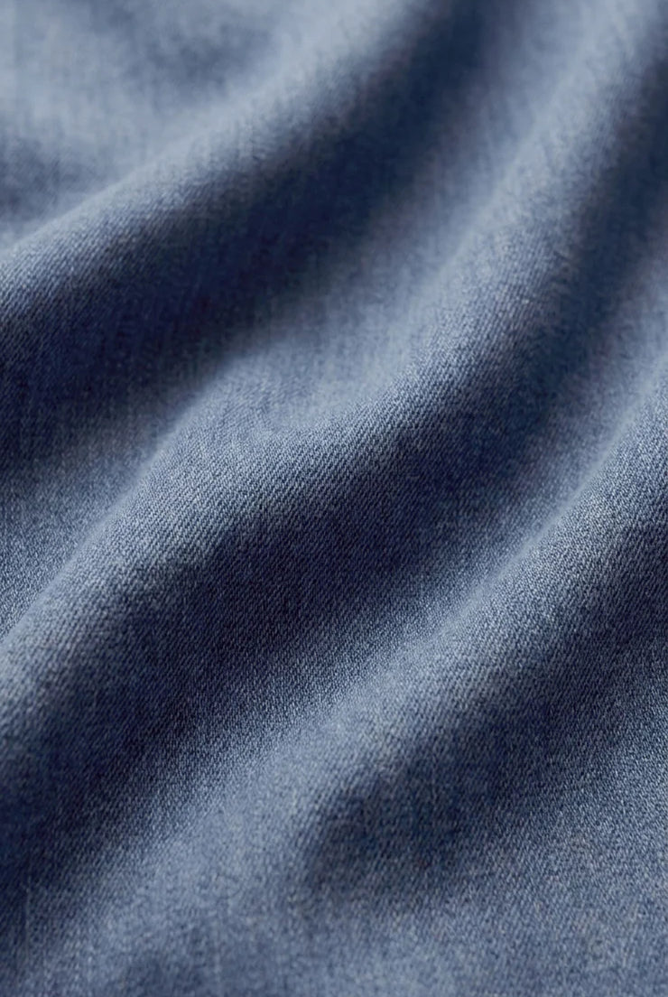 Close-up of soft indigo cotton twill fabric, showcasing its smooth texture, subtle diagonal weave, and lightweight construction with a naturally relaxed drape.