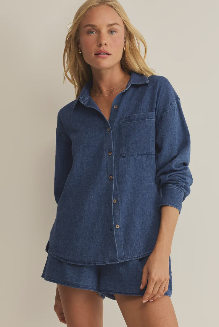 Woman wearing a blue denim shirt and shorts on a beige background