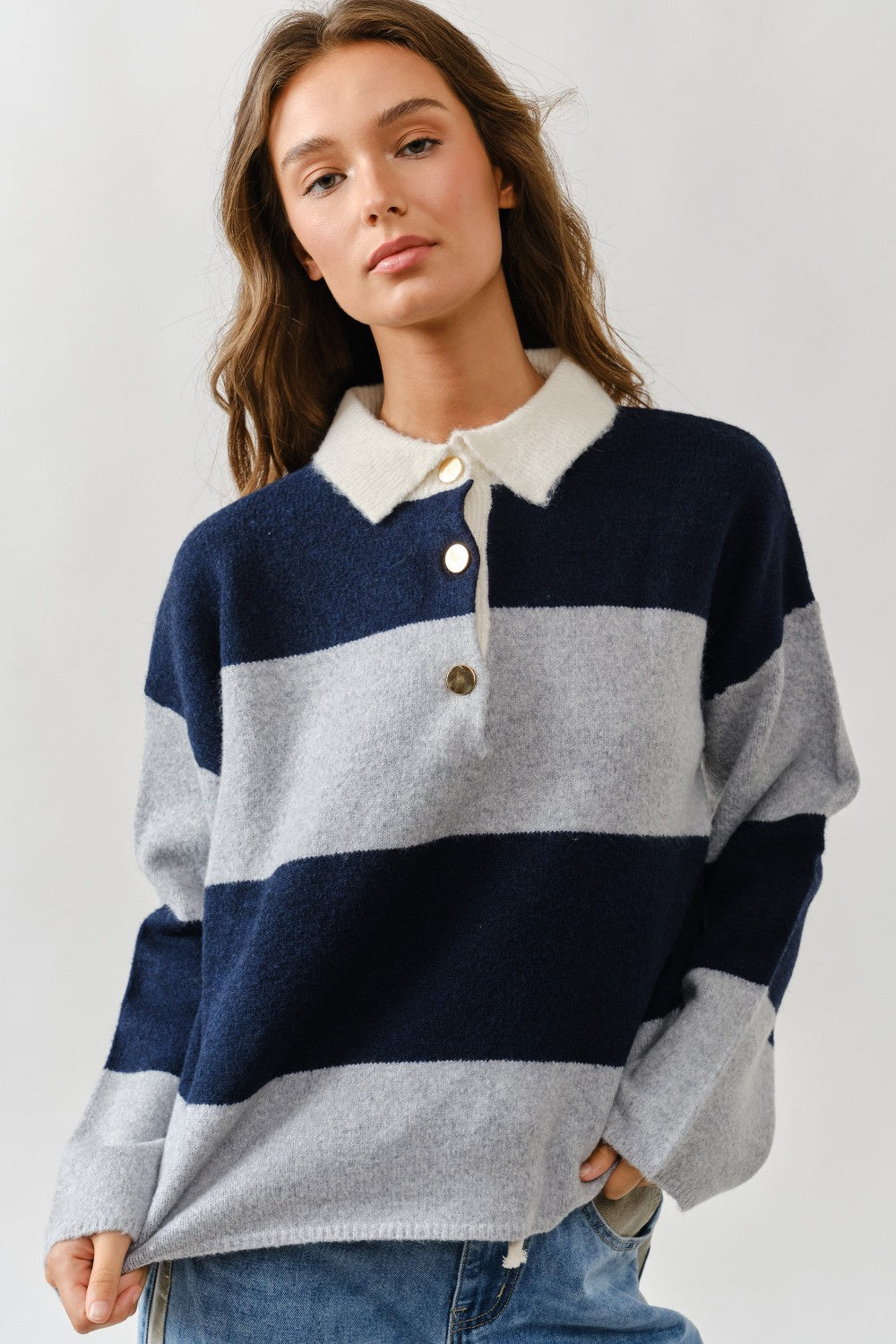 Woman wearing a striped sweater with a collar on a plain background