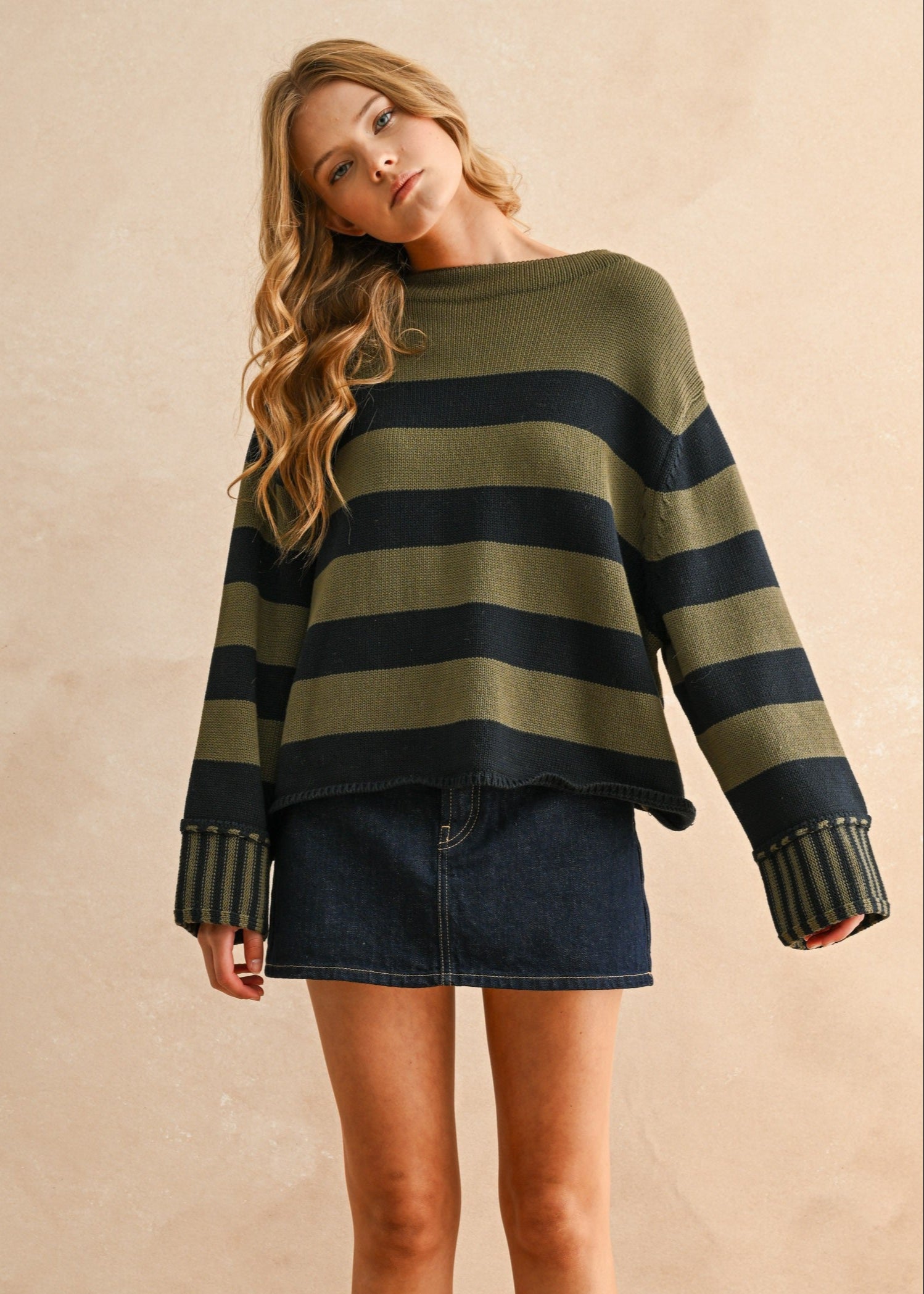 Woman wearing a striped sweater and denim skirt against a beige background