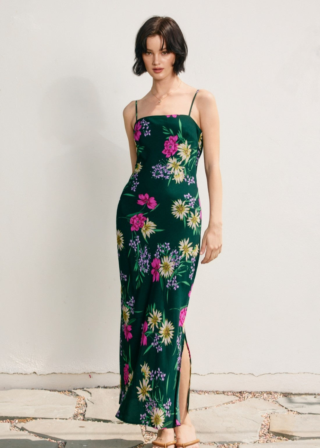 Woman wearing a green floral dress against a plain background