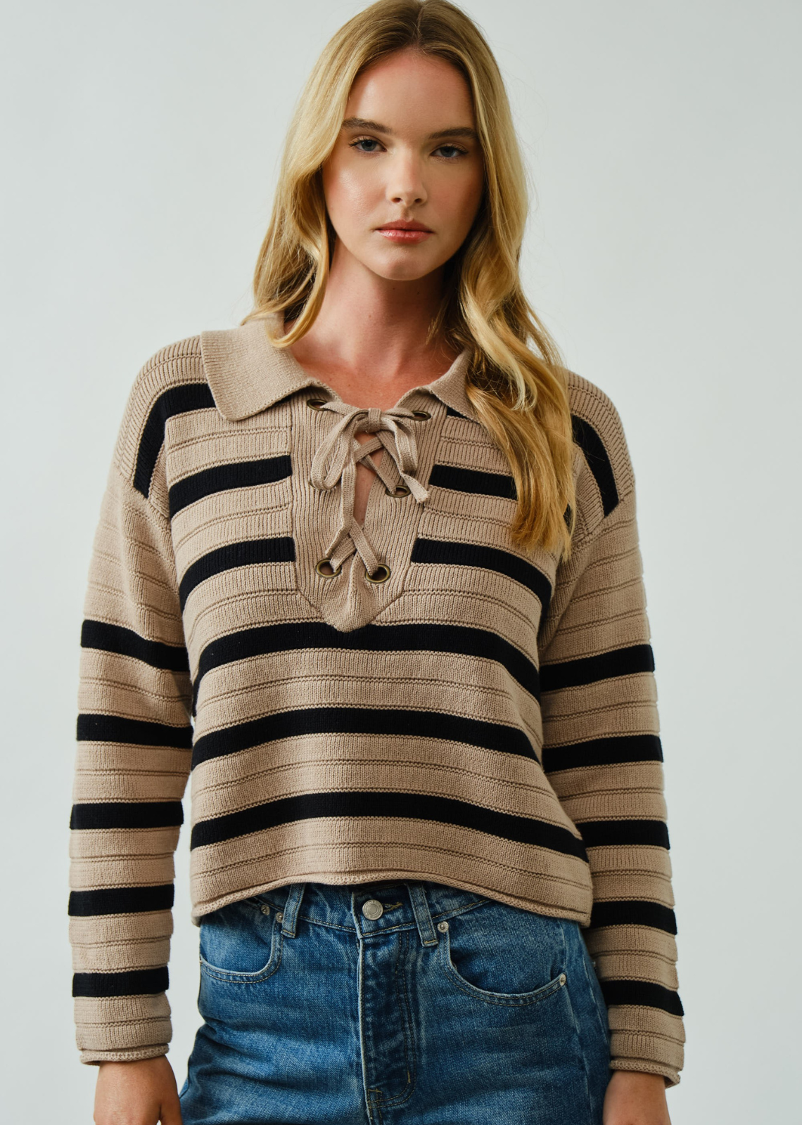 Woman wearing a striped sweater with a collar against a plain background