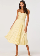 Woman wearing a light yellow pleated dress on a white background