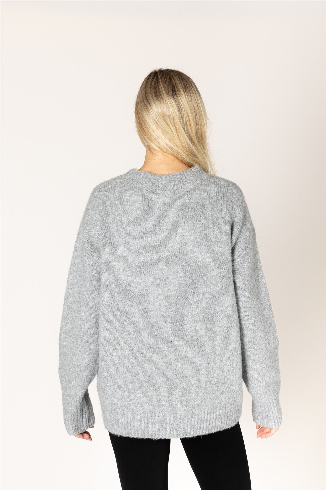 Dark grey oversized crewneck sweater featuring a bold black heart graphic on the front, with ribbed cuffs and hem.
