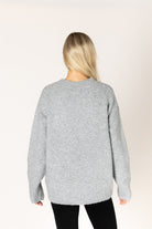 Dark grey oversized crewneck sweater featuring a bold black heart graphic on the front, with ribbed cuffs and hem.
