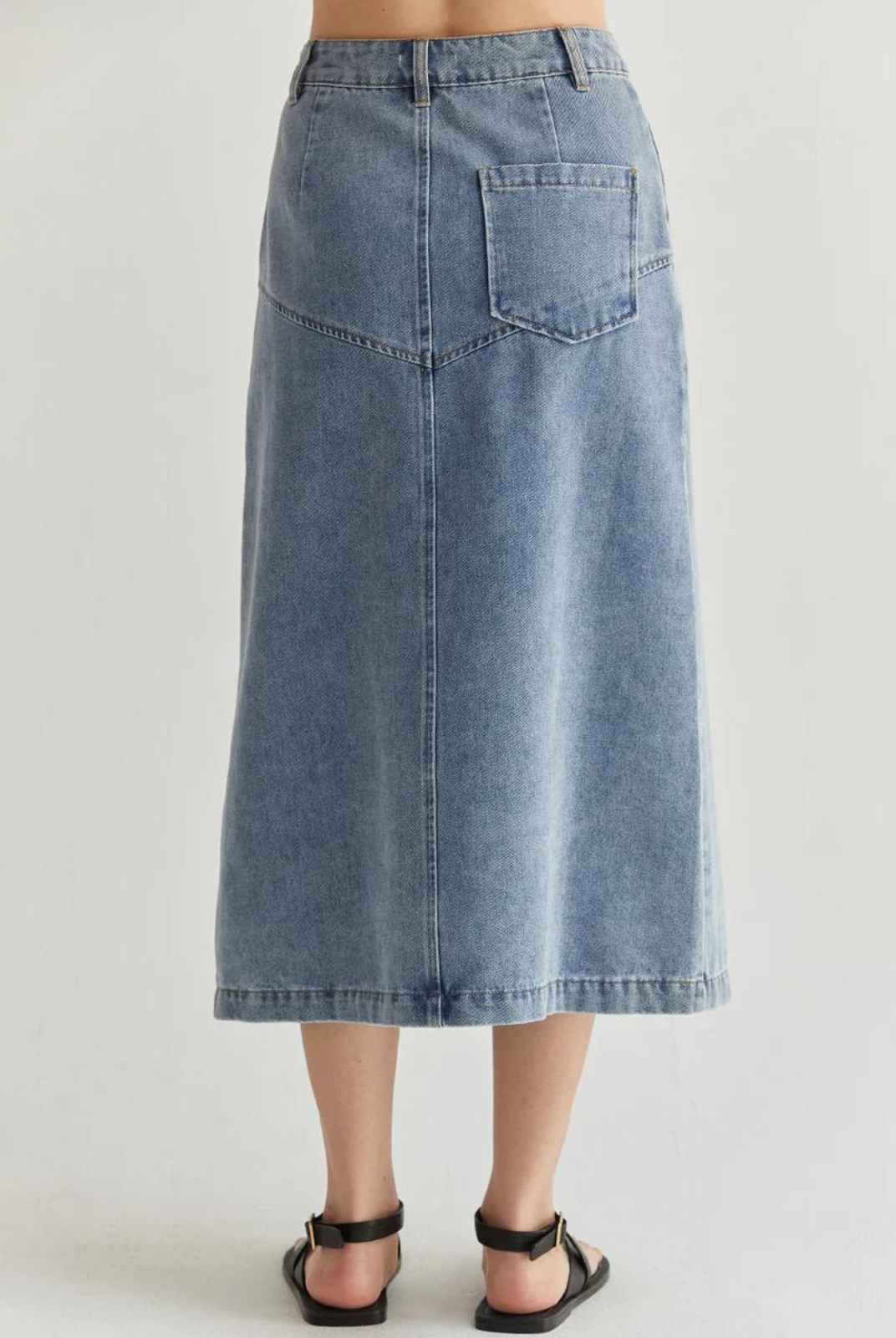 Brielle Denim Midi Skirt.The Brielle Denim Midi Skirt features a front button and zipper closure, side pockets, rear patch pocket, and angled seam on front hips that meets the inverted pleat detail.