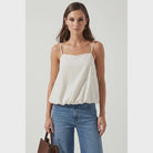 Off white bubble cami tank featuring a square neckline, adjustable spaghetti straps, a relaxed flowy silhouette, and a gathered bubble hem
