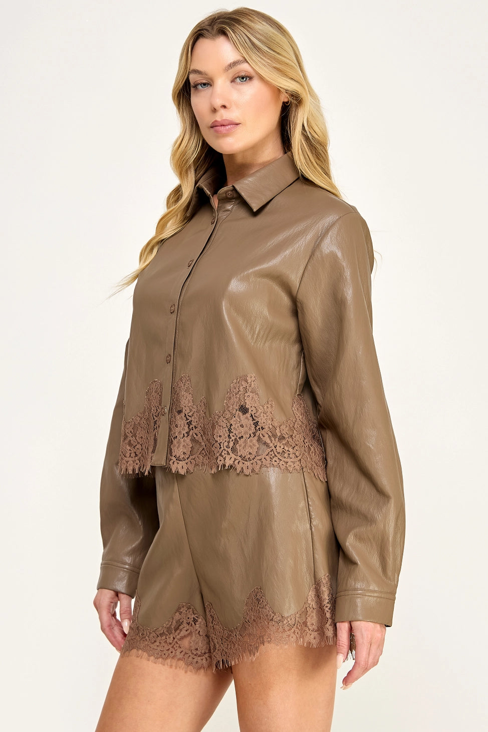 Clara Lace Trim Button-Down Top featuring a smooth faux leather finish, classic collar, long sleeves with buttoned cuffs, and delicate lace trim along the hem. Designed with a slightly cropped silhouette and a flattering, feminine fit. Pairs perfectly with the matching Clara Lace Trim Shorts for a chic, coordinated look.