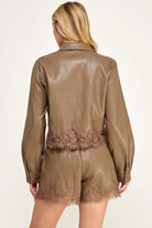 Clara Lace Trim Button-Down Top featuring a smooth faux leather finish, classic collar, long sleeves with buttoned cuffs, and delicate lace trim along the hem. Designed with a slightly cropped silhouette and a flattering, feminine fit. Pairs perfectly with the matching Clara Lace Trim Shorts for a chic, coordinated look.