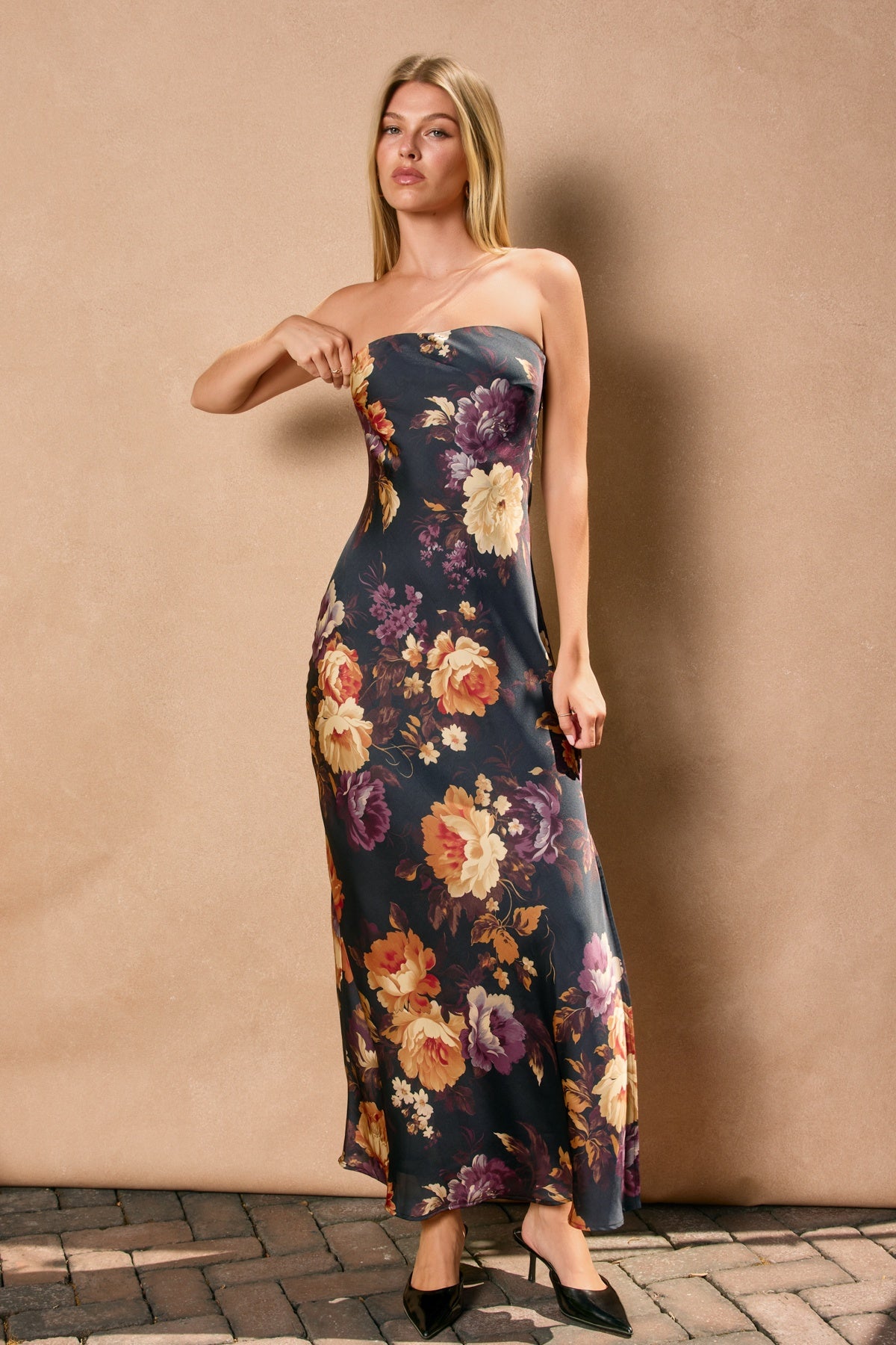Woman wearing a strapless floral dress against a beige wall.