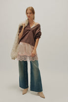 woman wearing a peach coloured satin mini skirt with a lace hem