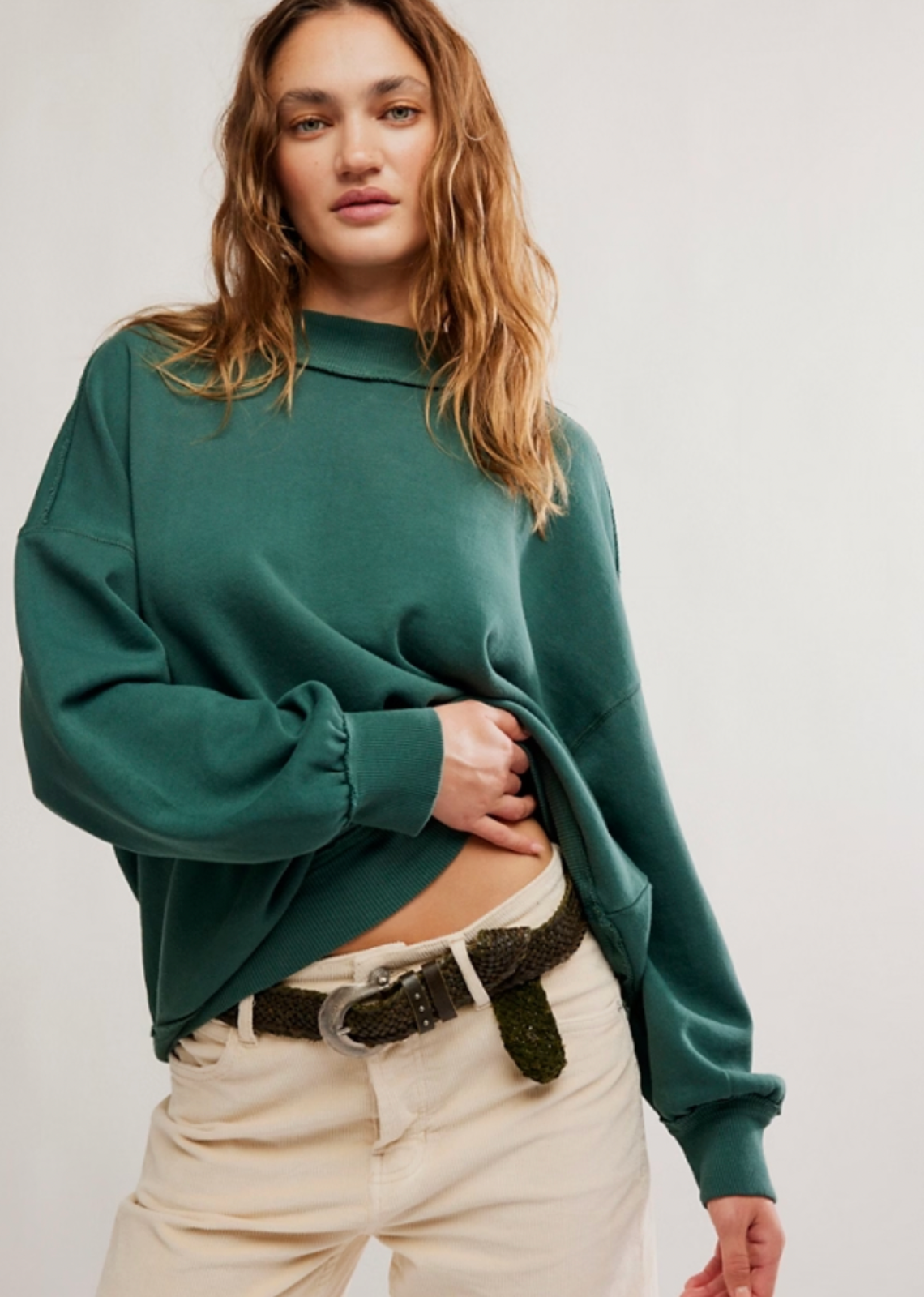 A girl wearing an oversized turtleneck with beige pants