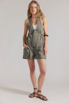 woman wearing a dark washed green romper with buttons at the front and with a v neck