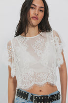 Woman wearing a white lace top with sheer sleeves
